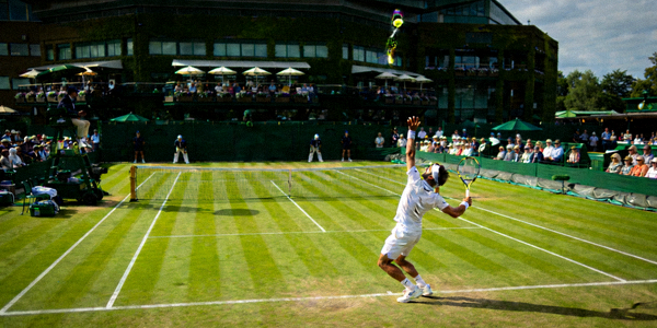 网球大满贯温布尔登锦标赛的绿色草地赛场，球员正在发球
